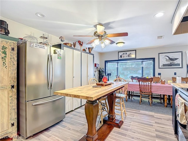 kitchen with visible vents, light wood-style flooring, freestanding refrigerator, and a ceiling fan