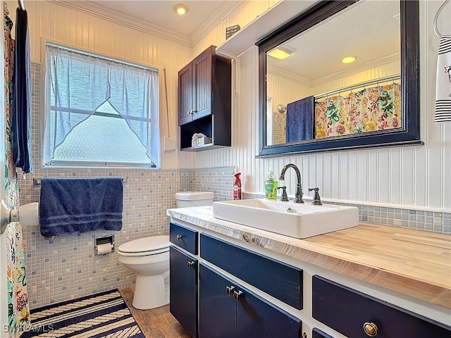 bathroom with tile walls, vanity, toilet, and crown molding