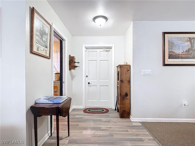 foyer featuring baseboards and wood finished floors