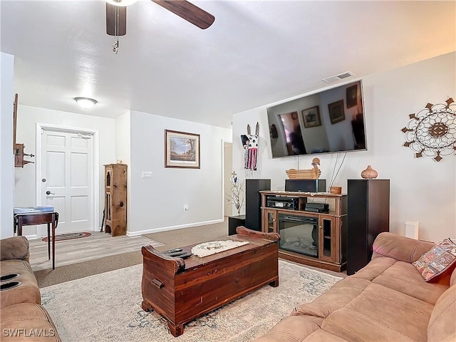 living area featuring carpet, ceiling fan, visible vents, and baseboards