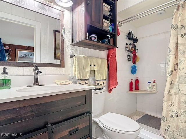 full bath featuring tiled shower, vanity, and toilet