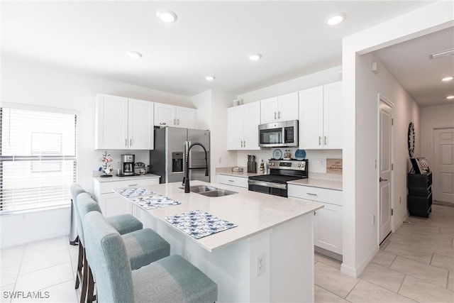 14239 Oviedo Pl, Fort Myers, FL 33905 - kitchen with stainless steel appliances, a sink, white cabinetry, a kitchen breakfast bar, and an island with sink