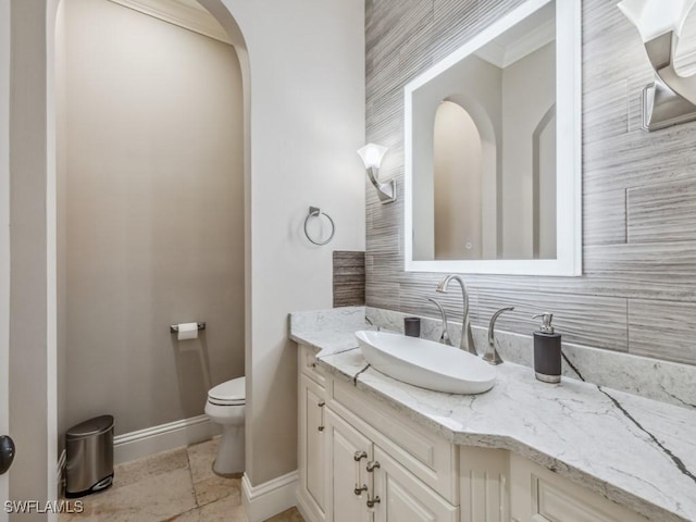 bathroom featuring vanity, toilet, baseboards, and ornamental molding