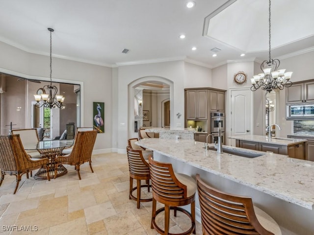 kitchen with a kitchen island with sink, a chandelier, a breakfast bar, and a sink