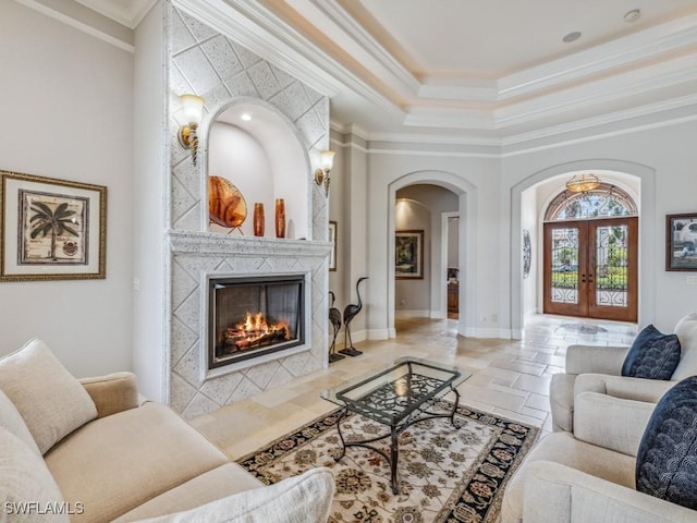 living room with french doors, stone tile flooring, a high end fireplace, and crown molding