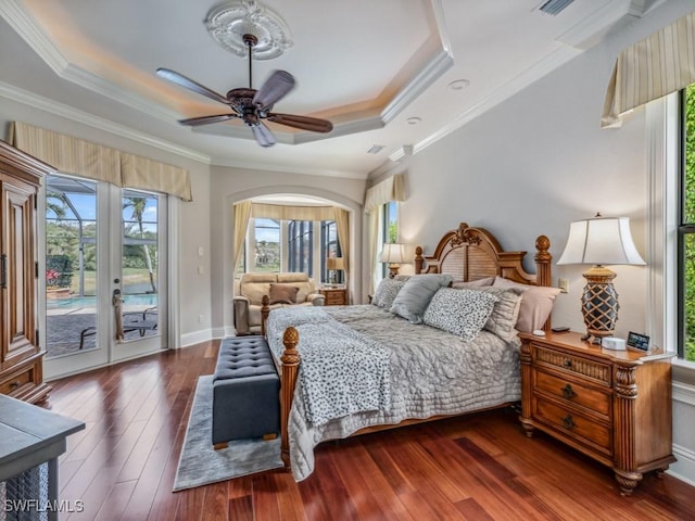 bedroom featuring access to outside, a tray ceiling, hardwood / wood-style floors, arched walkways, and crown molding