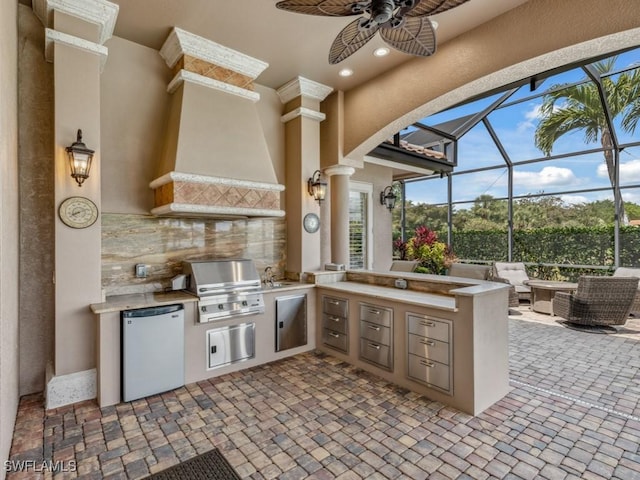 view of patio featuring ceiling fan, a lanai, area for grilling, and an outdoor kitchen