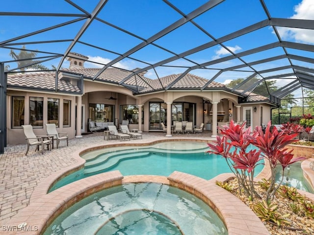 view of pool featuring a lanai, a pool with connected hot tub, ceiling fan, and a patio area