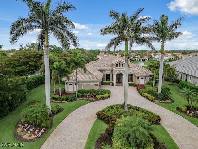 view of front facade with curved driveway, a tiled roof, a front lawn, and stucco siding