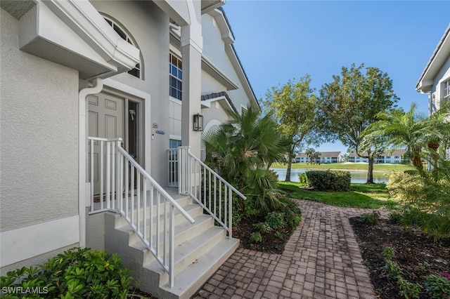 doorway to property with a water view and stucco siding