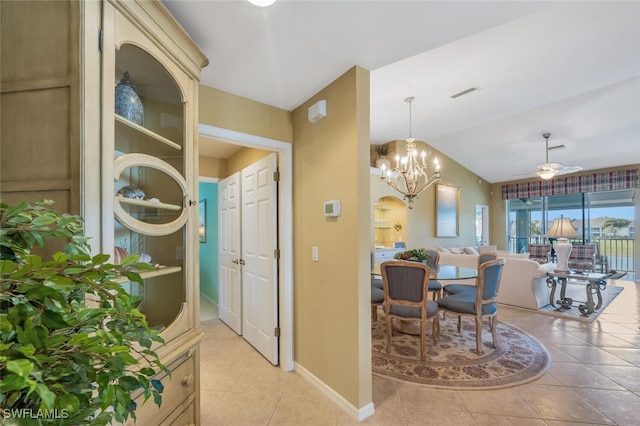 interior space featuring light tile patterned floors, visible vents, baseboards, vaulted ceiling, and ceiling fan with notable chandelier