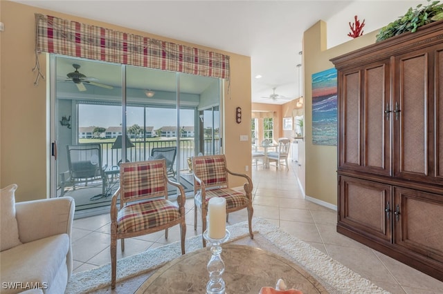 living area with light tile patterned floors, baseboards, and ceiling fan