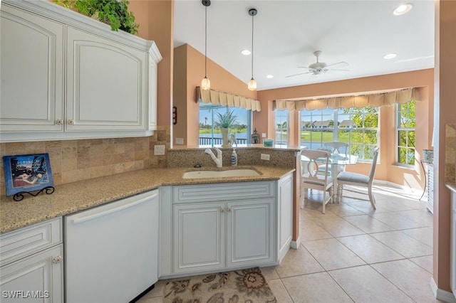 kitchen with light tile patterned floors, a peninsula, white dishwasher, a sink, and backsplash