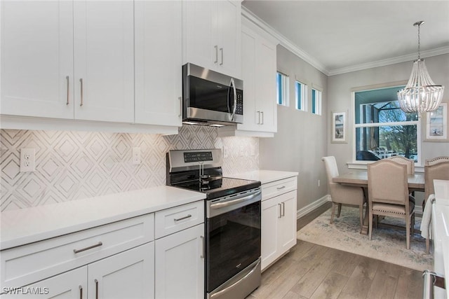 kitchen featuring backsplash, appliances with stainless steel finishes, white cabinets, crown molding, and light countertops