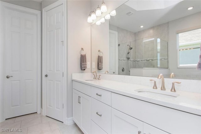 full bathroom with a tile shower, tile patterned flooring, double vanity, and a sink