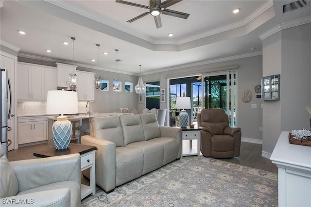 living area featuring visible vents, wood finished floors, a ceiling fan, and crown molding