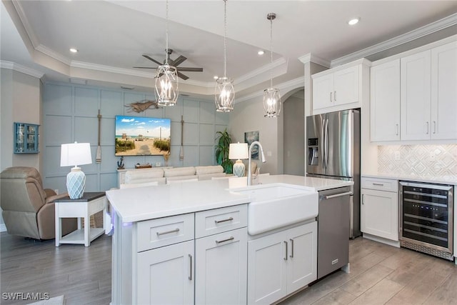 kitchen featuring stainless steel appliances, decorative backsplash, a sink, wine cooler, and a raised ceiling