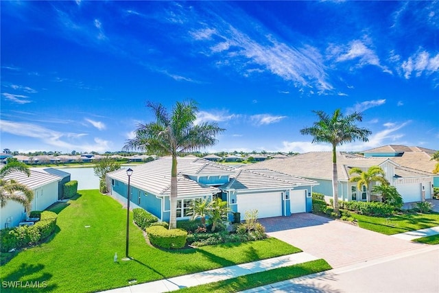 ranch-style house with a front lawn, a tiled roof, stucco siding, decorative driveway, and a garage