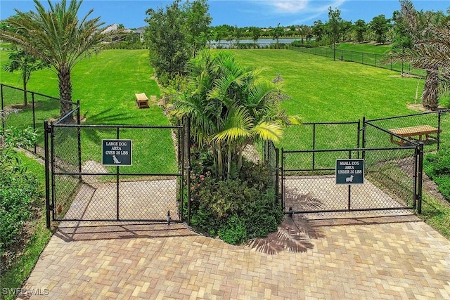 view of gate featuring a water view, a lawn, and fence