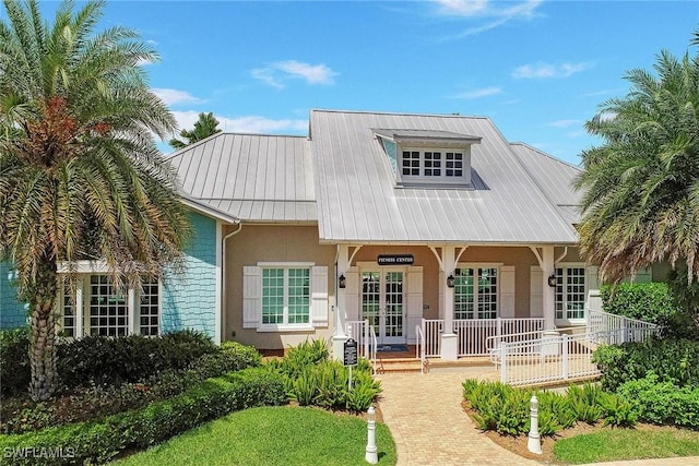 view of front of property with stucco siding, a porch, and metal roof