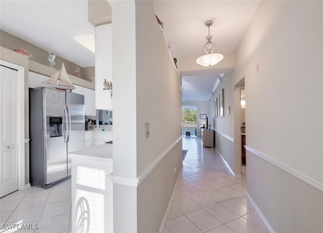 corridor featuring light tile patterned floors and baseboards