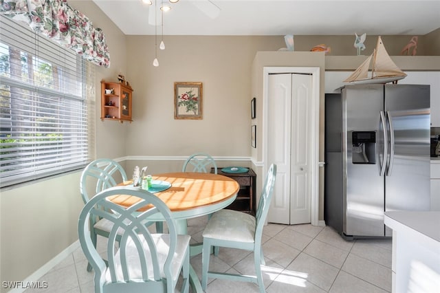 dining area with light tile patterned floors, baseboards, and a ceiling fan