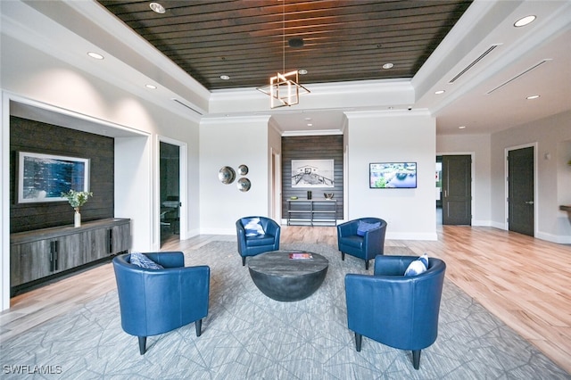 living room featuring a tray ceiling, baseboards, wood finished floors, and crown molding