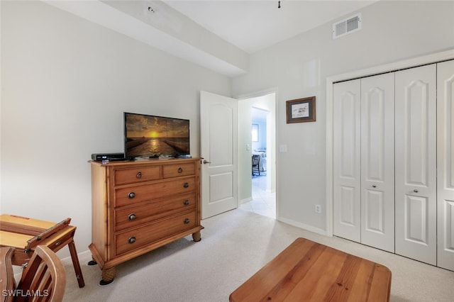 bedroom with light carpet, visible vents, baseboards, and a closet