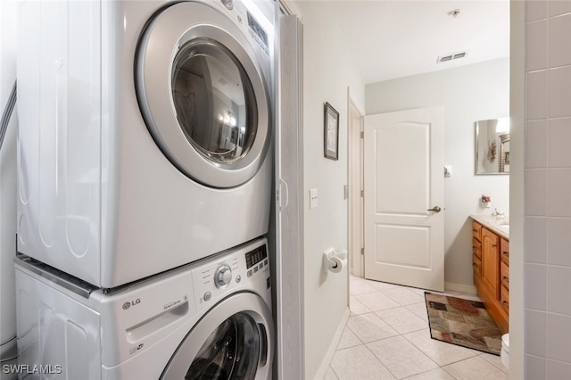 washroom featuring laundry area, light tile patterned flooring, visible vents, and stacked washer and clothes dryer