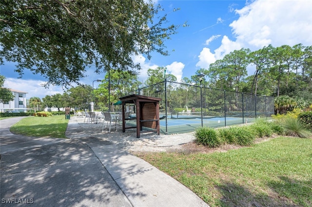 view of sport court with fence and a lawn