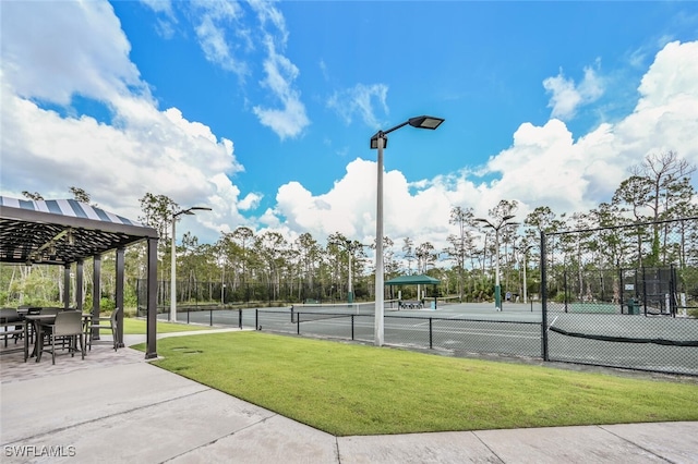 view of tennis court featuring a yard and fence