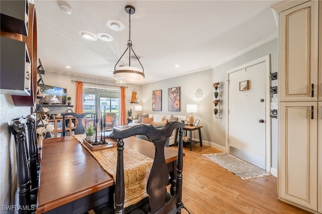 dining room with light wood finished floors, baseboards, and ornamental molding