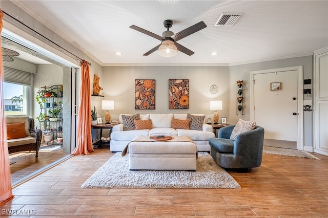 living area featuring ceiling fan, ornamental molding, visible vents, and wood tiled floor