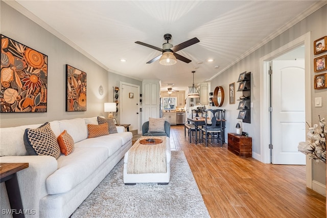 living area with ceiling fan, ornamental molding, recessed lighting, and light wood-style floors