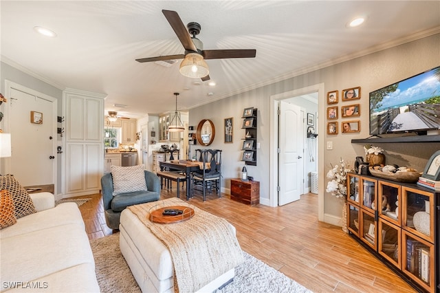 living room with ornamental molding, light wood-type flooring, and a ceiling fan