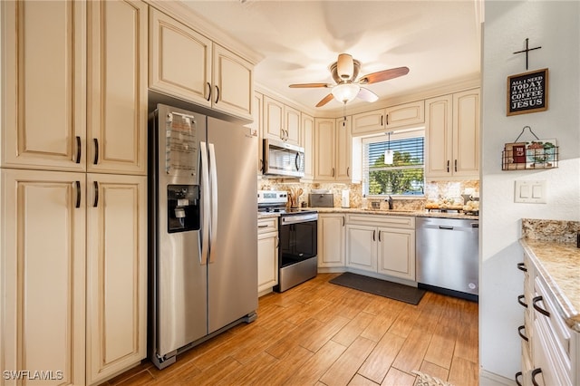 kitchen featuring tasteful backsplash, cream cabinets, appliances with stainless steel finishes, a ceiling fan, and light wood-style floors