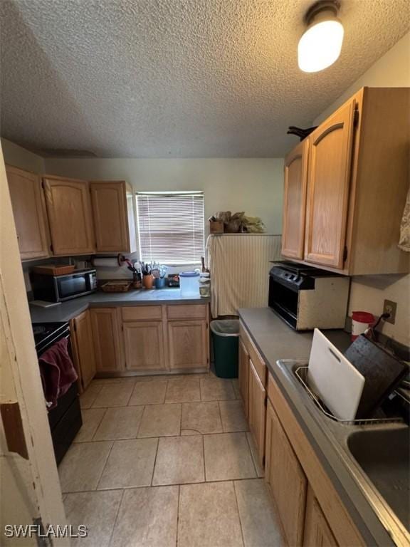 kitchen with stainless steel microwave, range, a textured ceiling, and light tile patterned floors