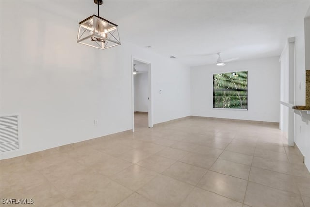 unfurnished room with light tile patterned flooring, visible vents, and ceiling fan with notable chandelier