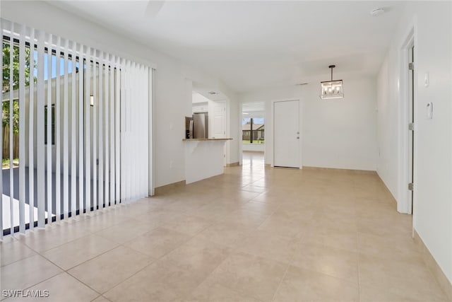 spare room featuring an inviting chandelier and light tile patterned floors