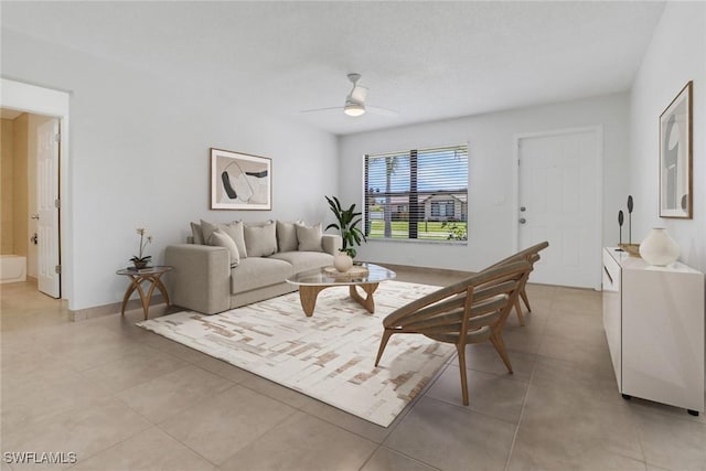 living area with ceiling fan, light tile patterned flooring, and baseboards