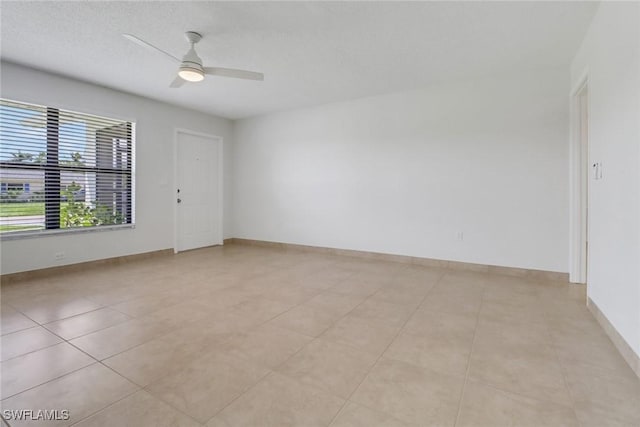 unfurnished room featuring ceiling fan, baseboards, and light tile patterned floors