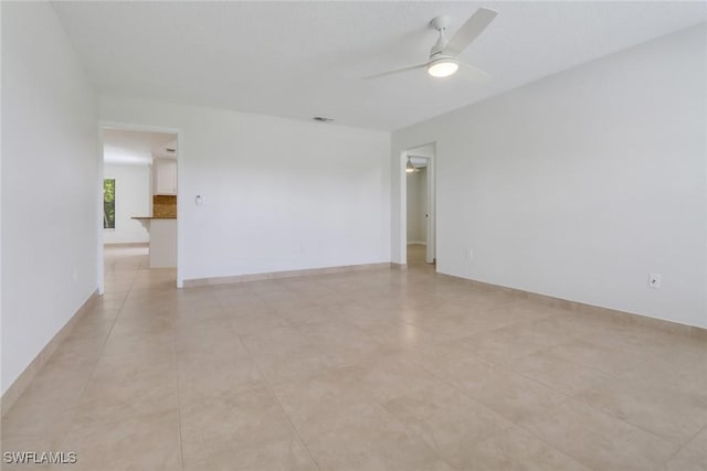 empty room with visible vents, a ceiling fan, and baseboards