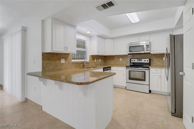 kitchen featuring stone counters, a peninsula, a sink, visible vents, and appliances with stainless steel finishes