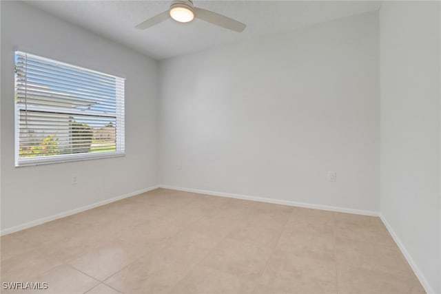 unfurnished room featuring light tile patterned flooring, a ceiling fan, and baseboards