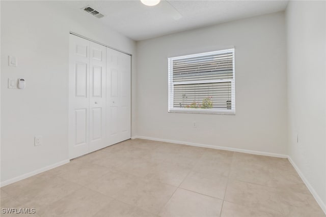 unfurnished bedroom with baseboards, visible vents, ceiling fan, and a closet