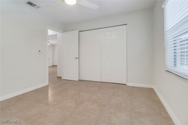 unfurnished bedroom with light tile patterned floors, baseboards, visible vents, and a closet