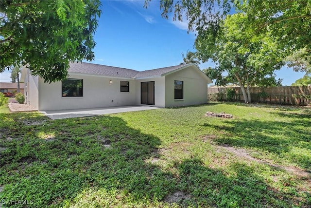 back of house with a yard, a patio area, fence, and stucco siding