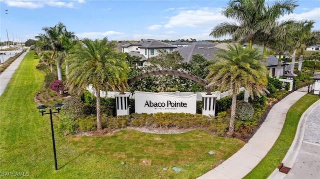 community sign featuring a lawn and a residential view