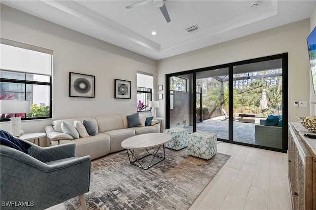 living room with a tray ceiling, visible vents, light wood finished floors, and recessed lighting