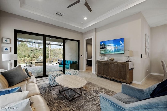 living area featuring light wood finished floors, baseboards, visible vents, a tray ceiling, and recessed lighting